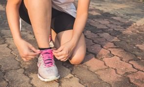 mulher amarrando tenis